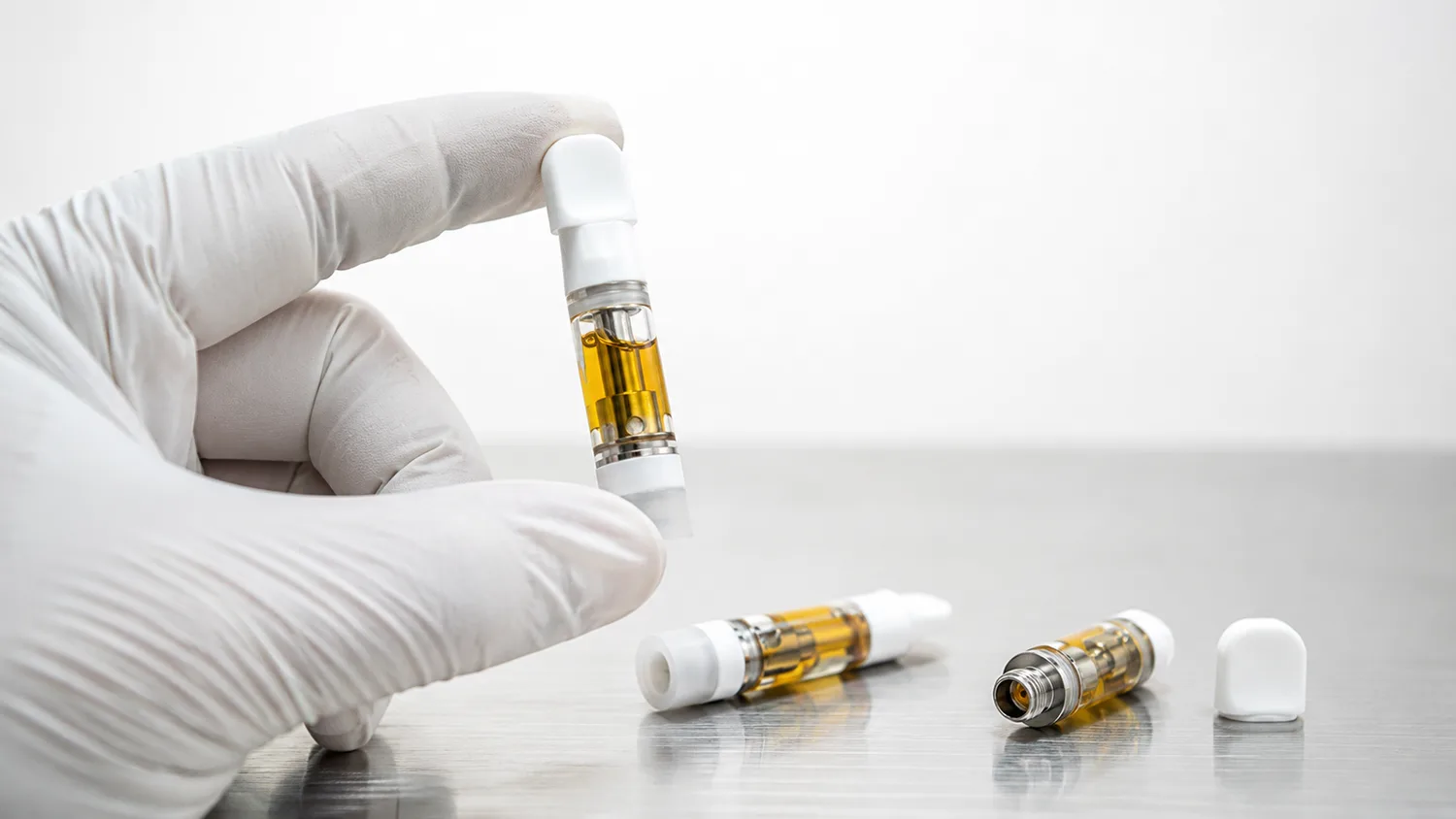 Operator inspecting vape cartridges for loose caps, leaks and product waste after capping
